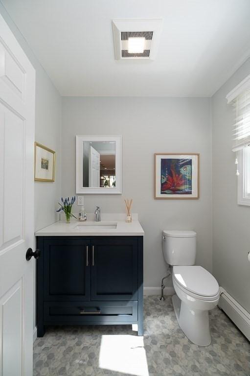 half bath with visible vents, baseboards, a baseboard radiator, vanity, and toilet