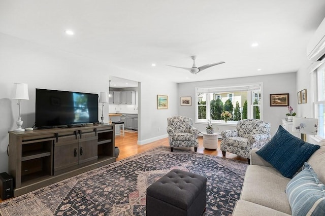 living room with recessed lighting, ceiling fan, a wall mounted AC, and light wood finished floors