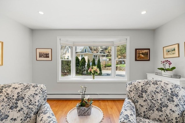 living area with light wood-type flooring, a baseboard heating unit, and recessed lighting