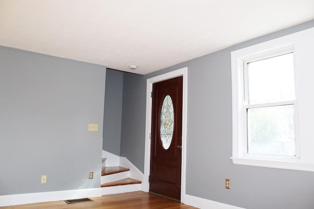 entryway featuring stairway, visible vents, baseboards, and wood finished floors
