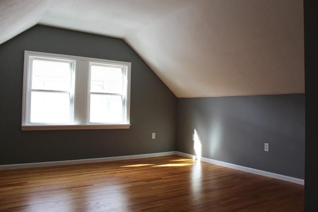 additional living space with lofted ceiling, wood finished floors, and baseboards