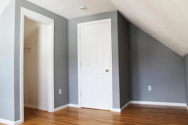 bonus room with lofted ceiling, baseboards, and wood finished floors