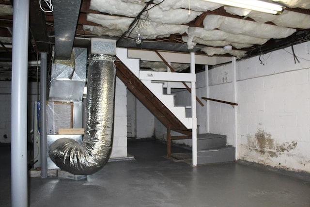 unfinished below grade area with stairway, heating unit, and concrete block wall