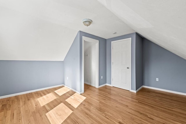 bonus room with baseboards, vaulted ceiling, and wood finished floors
