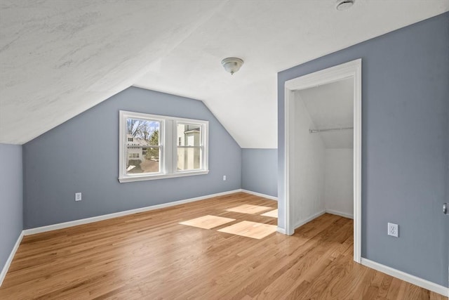 bonus room with baseboards, vaulted ceiling, and wood finished floors