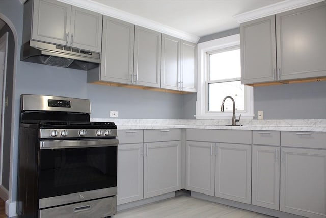 kitchen featuring a sink, gas stove, gray cabinetry, and under cabinet range hood
