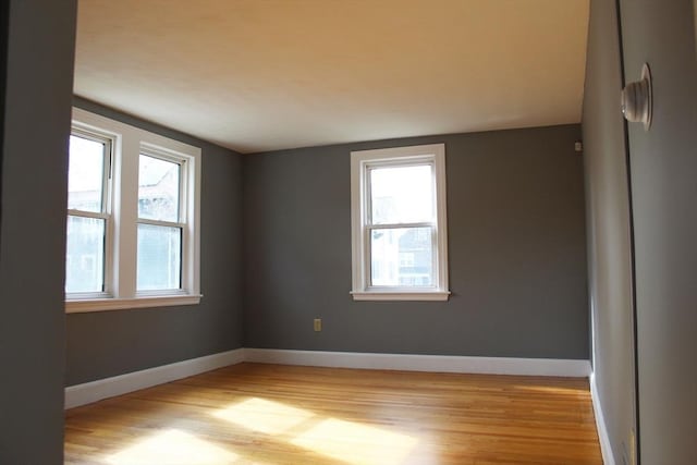 unfurnished room featuring a wealth of natural light, light wood-style flooring, and baseboards