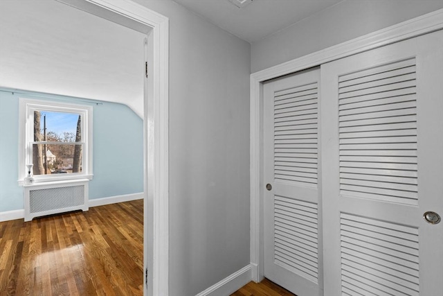 corridor featuring lofted ceiling, hardwood / wood-style floors, and radiator heating unit