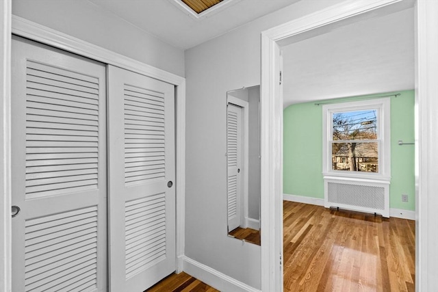 hall featuring vaulted ceiling, radiator, and hardwood / wood-style floors