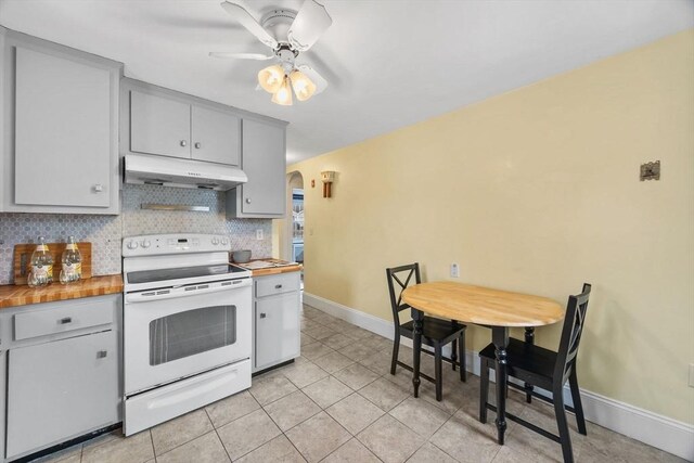 kitchen featuring electric stove, light tile patterned floors, ceiling fan, butcher block counters, and decorative backsplash