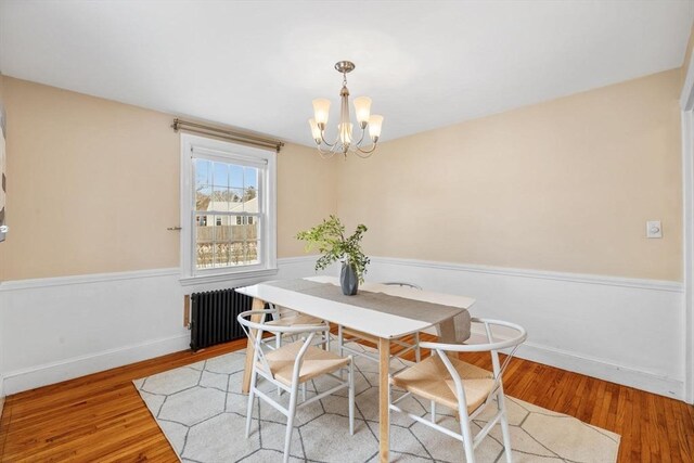 dining room featuring a notable chandelier, radiator heating unit, and light wood-type flooring