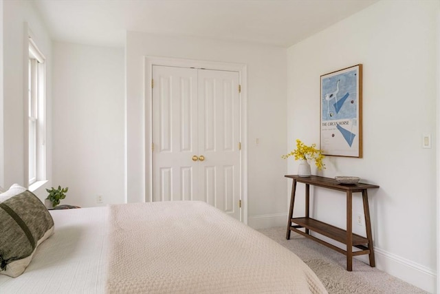 carpeted bedroom with a closet and baseboards