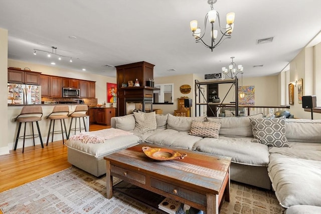 living room featuring an inviting chandelier, visible vents, and light wood-type flooring