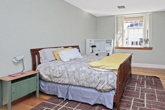 bedroom featuring visible vents, baseboards, and wood finished floors