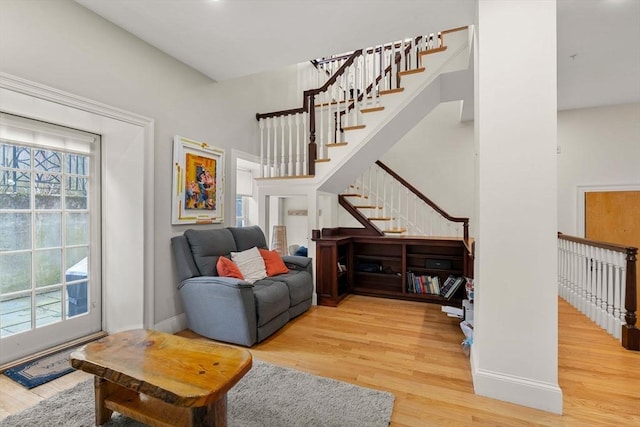 living room with baseboards, wood finished floors, and stairway