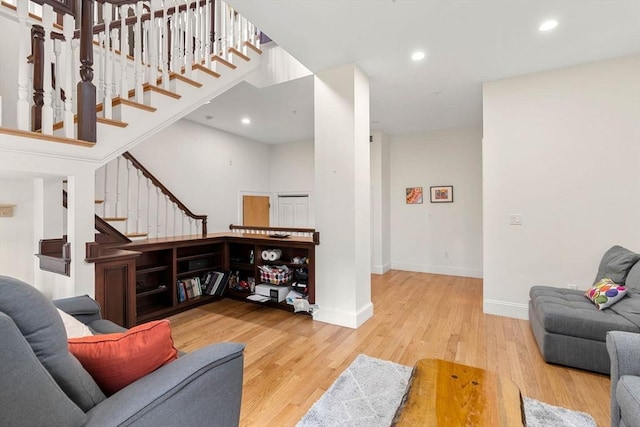 living room featuring baseboards, recessed lighting, wood finished floors, and stairway