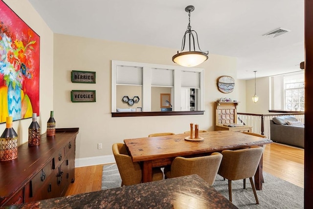 dining space with visible vents, baseboards, and wood finished floors