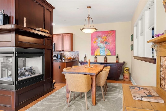 dining room with light wood-type flooring and a multi sided fireplace