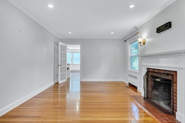 unfurnished living room featuring light wood-style floors, baseboards, a fireplace, and radiator heating unit