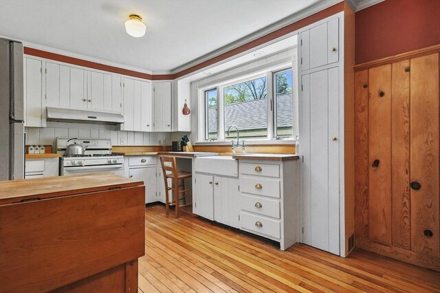 47 Stetson, Haverhill, MA 01835 - kitchen featuring white gas range, under cabinet range hood, a sink, butcher block counters, and light wood finished floors