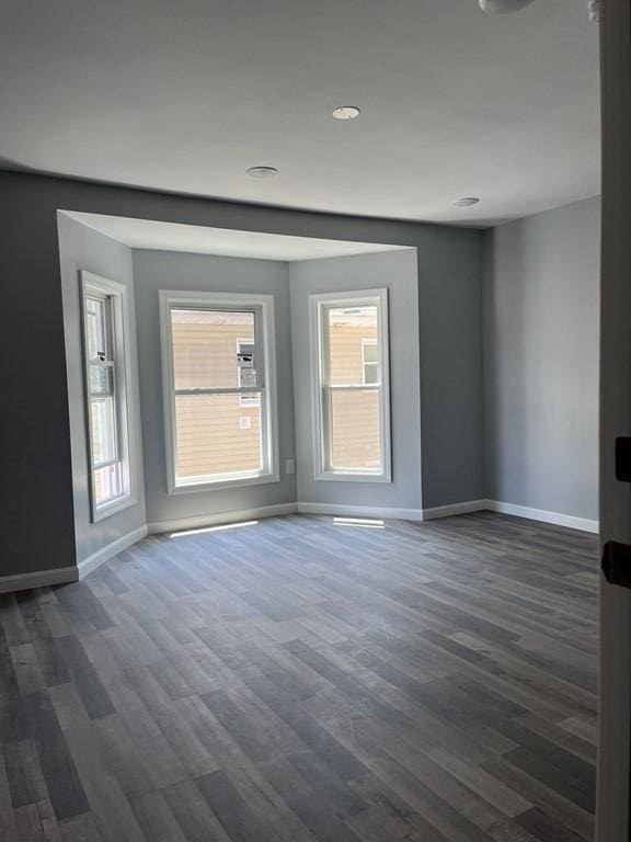 spare room featuring baseboards and dark wood finished floors