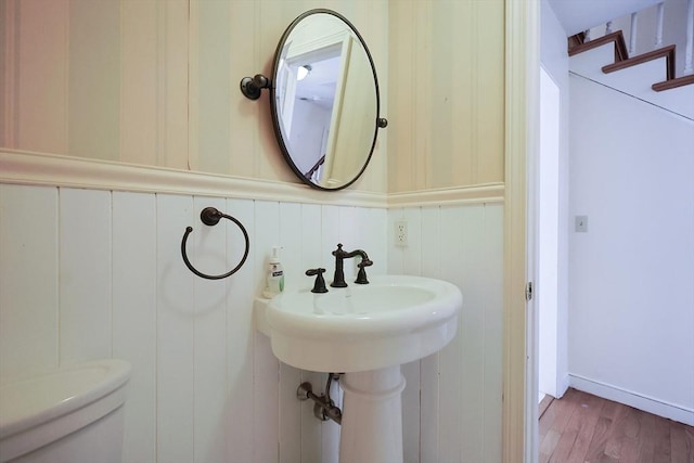 bathroom with hardwood / wood-style flooring, toilet, and wood walls