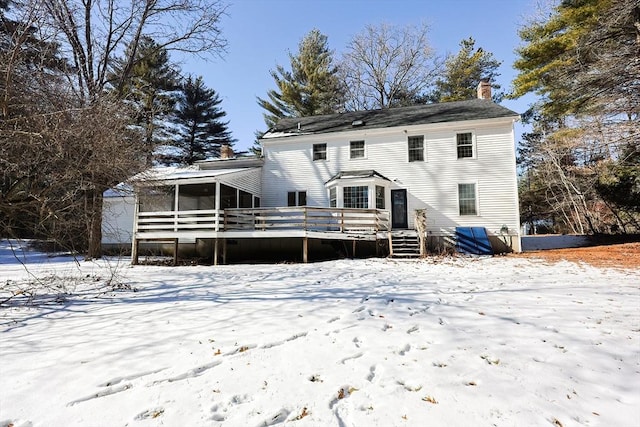 snow covered rear of property with a wooden deck