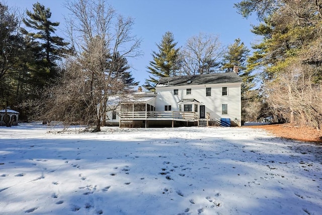 snow covered property featuring a sunroom and a deck