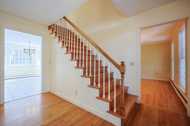 staircase with a baseboard radiator, wood-type flooring, and a chandelier