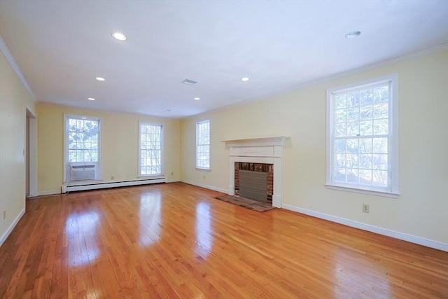 unfurnished living room with baseboard heating, ornamental molding, a brick fireplace, and light wood-type flooring