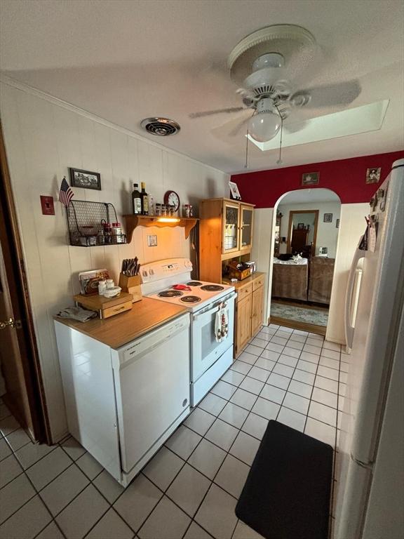 kitchen featuring white appliances, light tile patterned floors, arched walkways, ceiling fan, and glass insert cabinets