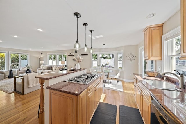 kitchen with a healthy amount of sunlight, a sink, light wood finished floors, and dishwasher