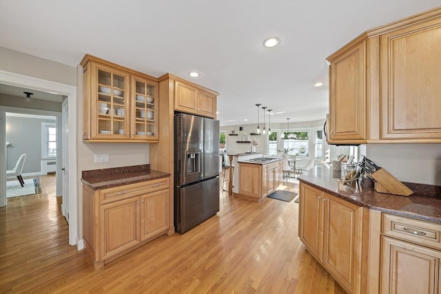 kitchen with stainless steel fridge with ice dispenser, light wood-style floors, recessed lighting, a kitchen island, and glass insert cabinets