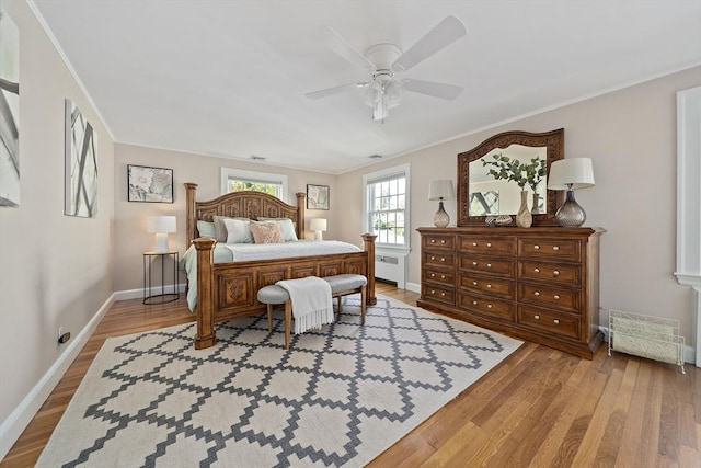 bedroom with crown molding, baseboards, radiator, and light wood-type flooring