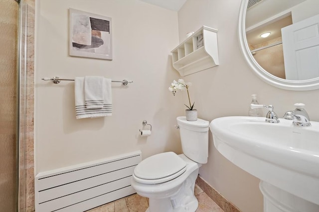 bathroom with a sink, baseboard heating, toilet, baseboards, and a shower