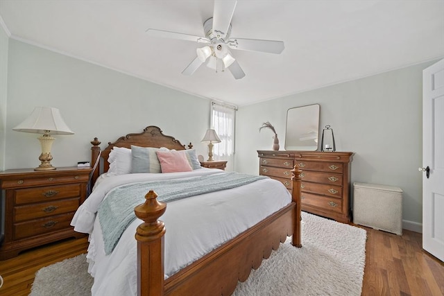 bedroom with baseboards, ornamental molding, a ceiling fan, and wood finished floors