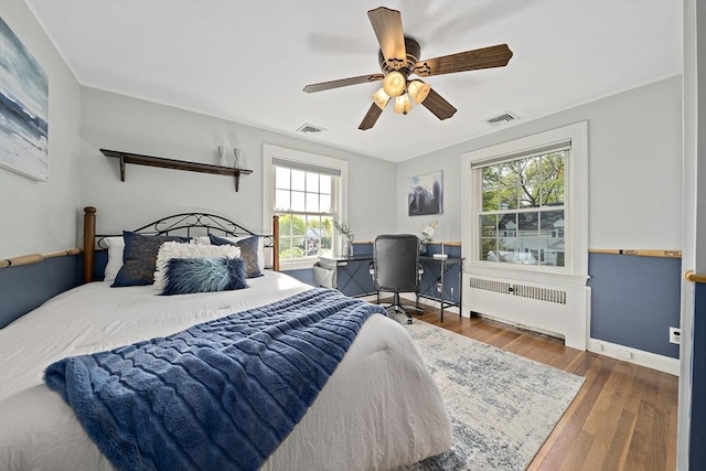bedroom featuring radiator heating unit, ceiling fan, wood finished floors, and visible vents