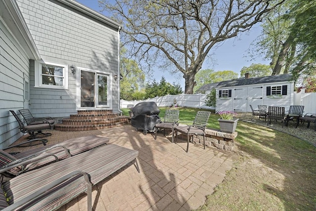 view of patio featuring a storage shed, an outdoor structure, a fenced backyard, entry steps, and a grill
