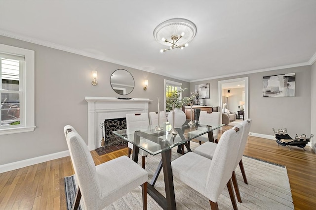 dining area with crown molding, baseboards, light wood-style flooring, and a chandelier