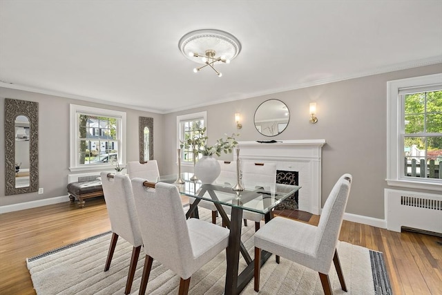 dining space featuring crown molding, an inviting chandelier, radiator, baseboards, and wood finished floors