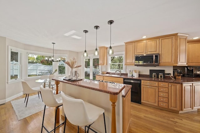 kitchen featuring stainless steel microwave, black dishwasher, light wood-type flooring, and a wealth of natural light