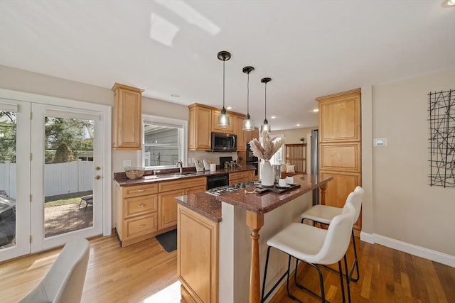 kitchen with light wood-type flooring, a sink, a kitchen island, and a kitchen bar