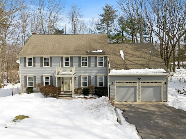 colonial inspired home featuring aphalt driveway and an attached garage