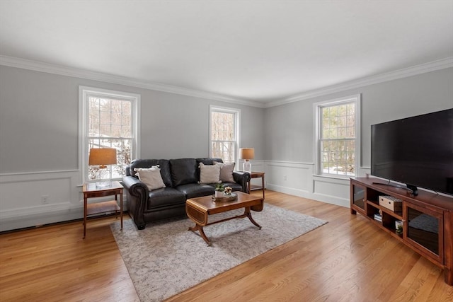 living room featuring a wainscoted wall, crown molding, and light wood finished floors