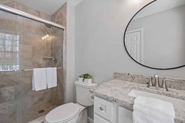 bathroom featuring a stall shower, toilet, and vanity