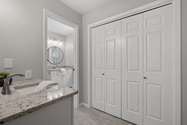 bathroom with vanity, baseboards, and a closet