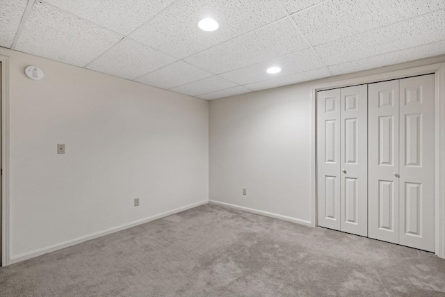 unfurnished bedroom with recessed lighting, a closet, baseboards, carpet, and a paneled ceiling