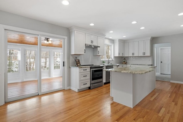 kitchen featuring under cabinet range hood, backsplash, white cabinetry, light wood-style floors, and appliances with stainless steel finishes