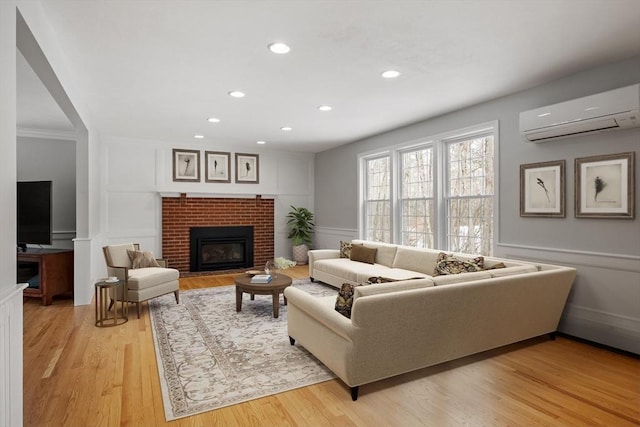 living area with a brick fireplace, a decorative wall, light wood-style floors, and a wall mounted AC