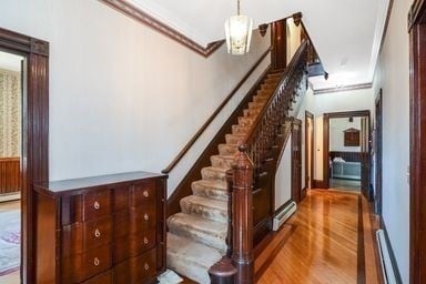 staircase with hardwood / wood-style flooring and ornamental molding